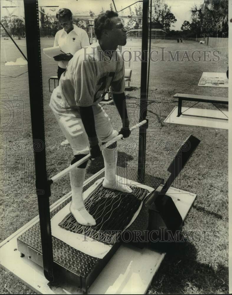 1976 Press Photo Football player Rod McNeill pulls on bar during training- Historic Images