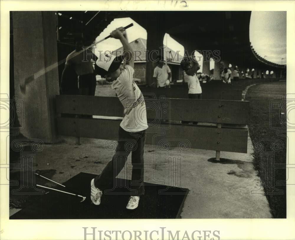 1984 Press Photo Youth golfer Travis Schmid hits golf balls at a driving range- Historic Images