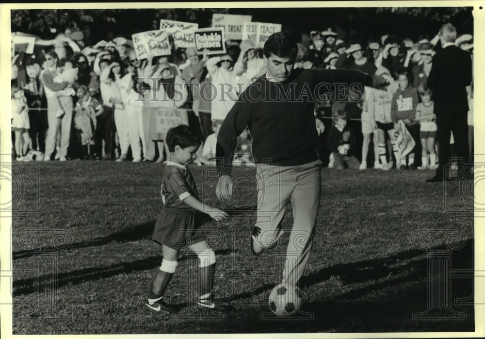 1988 Michael Dukakis demonstrates soccer skills with CA children - Historic Images