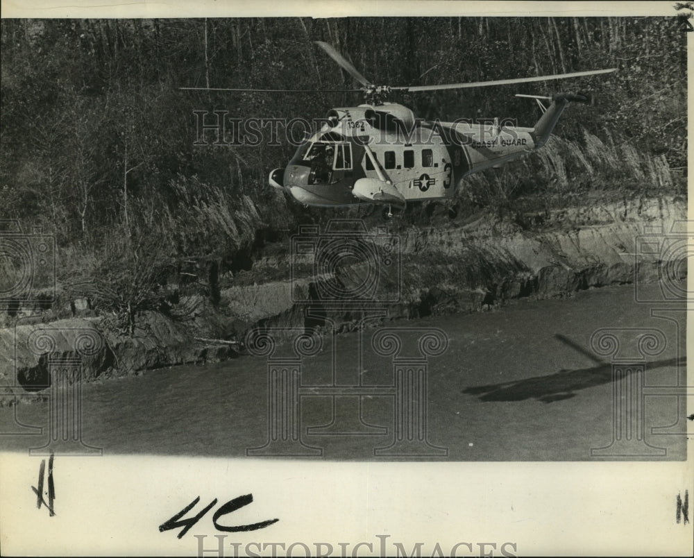 1968 A helicopter searches the river bank for missing boat crewmen - Historic Images