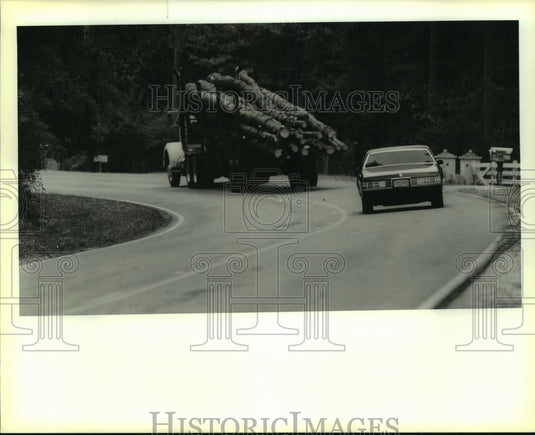 1989 Press Photo A car follows a log truck into Deadman's curve near Covington - Historic Images
