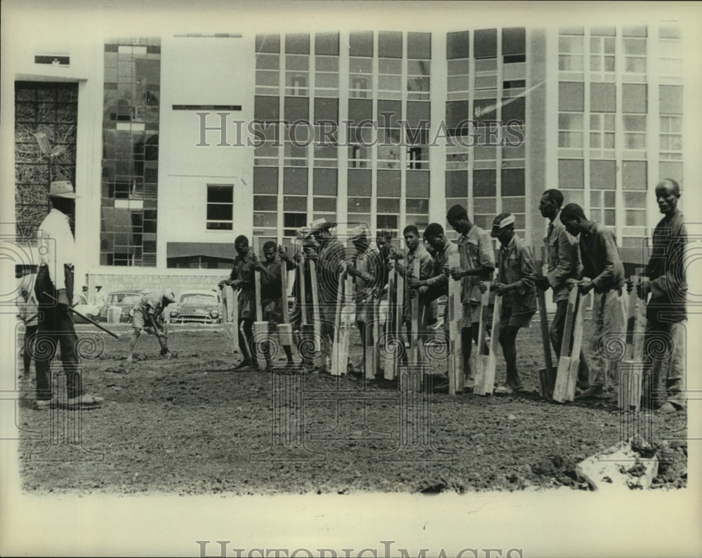 1963 Ethiopian workers build a road by hand; background, modern bldg - Historic Images