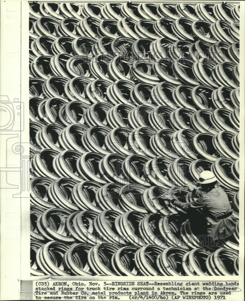 1971 Goodyear Tire technician surrounded by tire rims in Akron - Historic Images