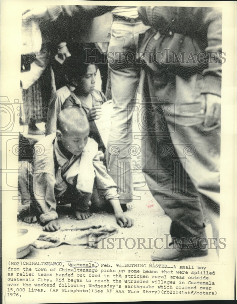 1976 Chimaltenango youth picks up spilled beans from relief aid-Historic Images