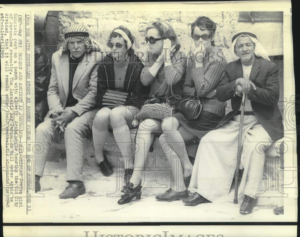 1969 Mini-skirted girl tourists with with elderly Arabs in Jerusalem - Historic Images