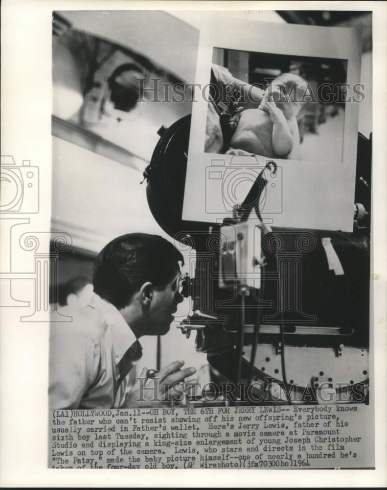 1964 Press Photo Jerry Lewis places photo enlargement of new son on movie camera - Historic Images