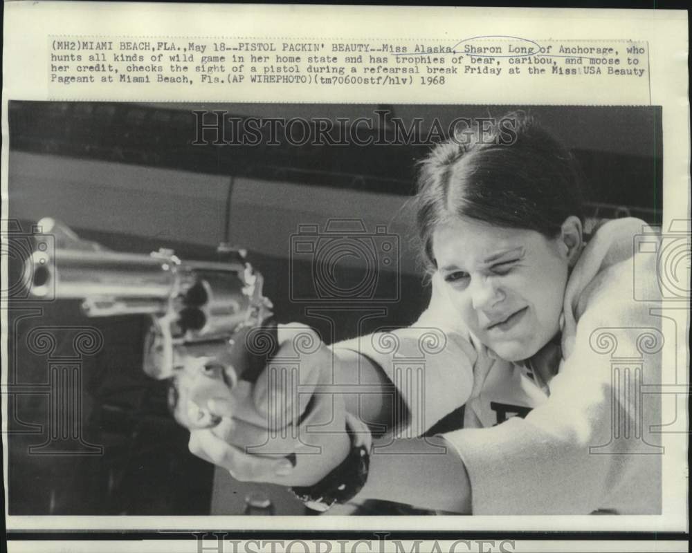 1968  Sharon Stone, Miss Alaska, checks pistol sight - Historic Images