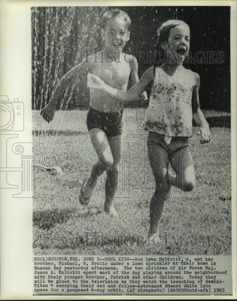 1965 Ann Lynn and Michael McDivitt frolic under lawn sprinkler - Historic Images