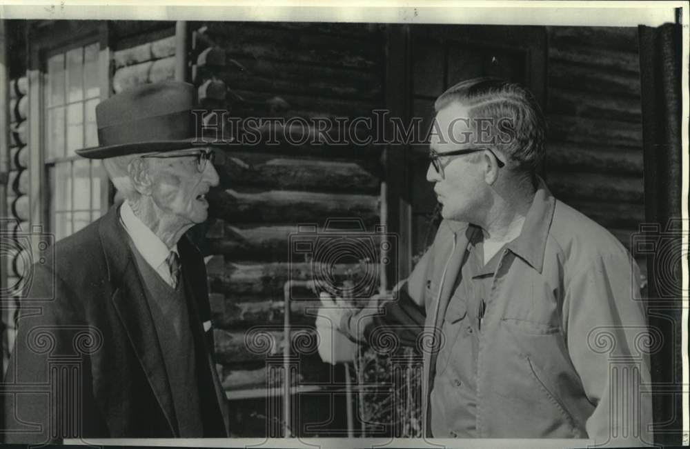 1973 John O&#39;Neal chats with Thomas over log cabin construction in LA - Historic Images