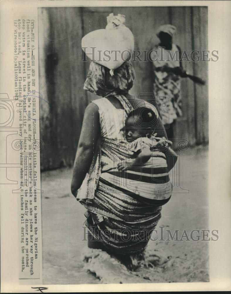 1962 Lagos mother and child walk flooded streets - Historic Images