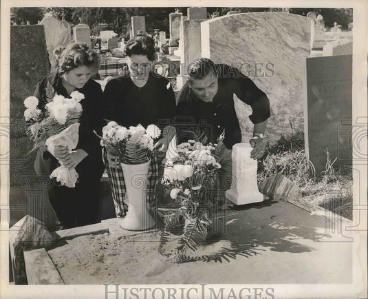 1962 Wilhemina and Mr. & Mrs. Burns place flowers on mother's grave. - Historic Images