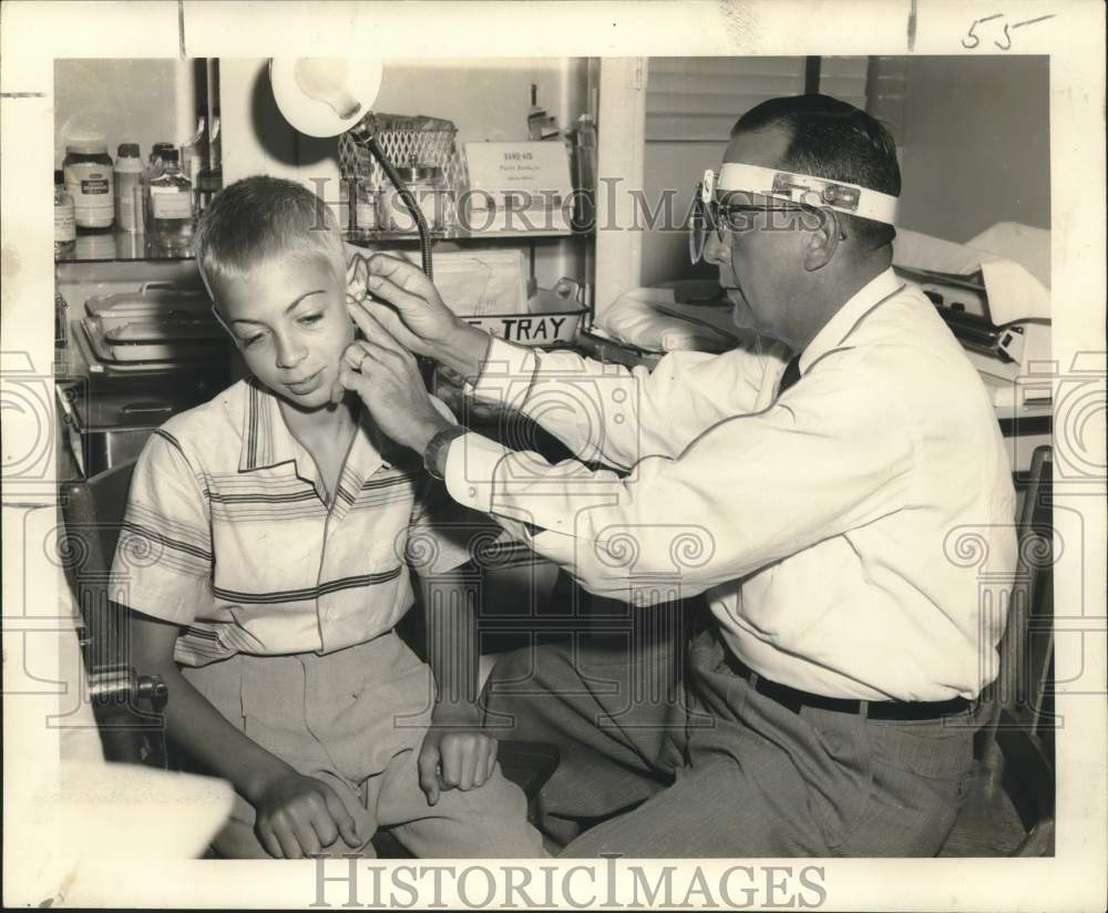 1957 Dr. Paul Lastrapes checks the ears of student Ricky Moore - Historic Images