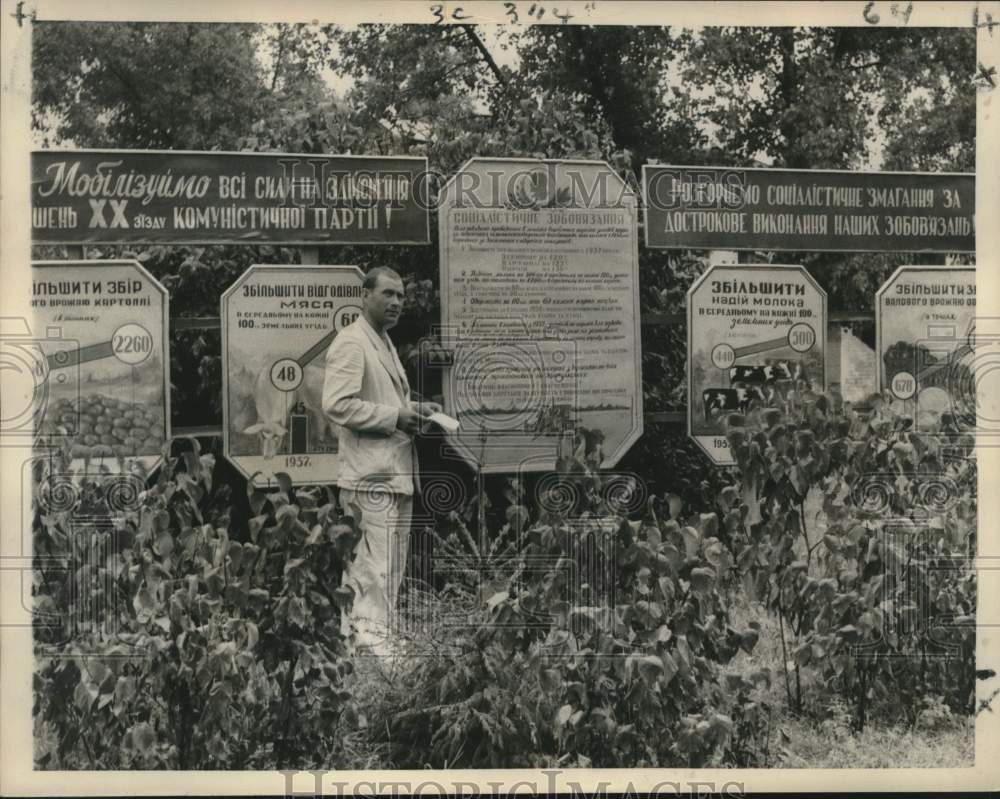 1958 A man stands in front of &quot;Outproduce America&quot; banners near Kiev-Historic Images