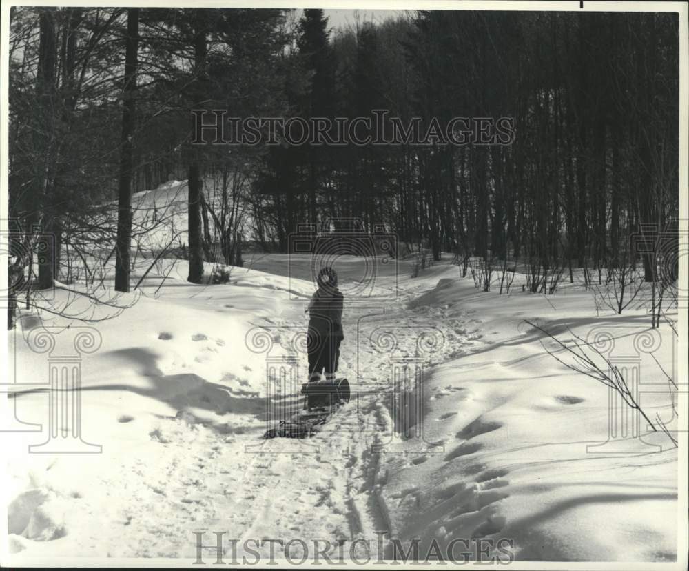 1976 Press Photo Kid drags a toboggan during winter in Canada - pia02318- Historic Images