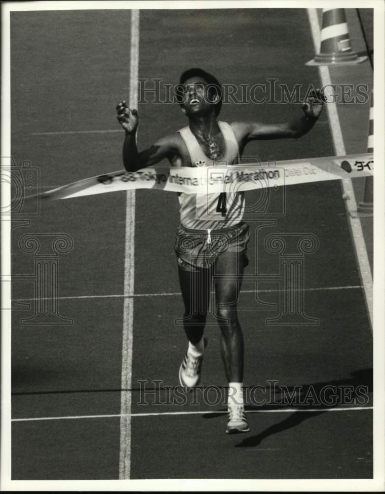 1988 Press Photo Runner Abebe Mekonen crosses finish line, Marathon, Tokyo - Historic Images