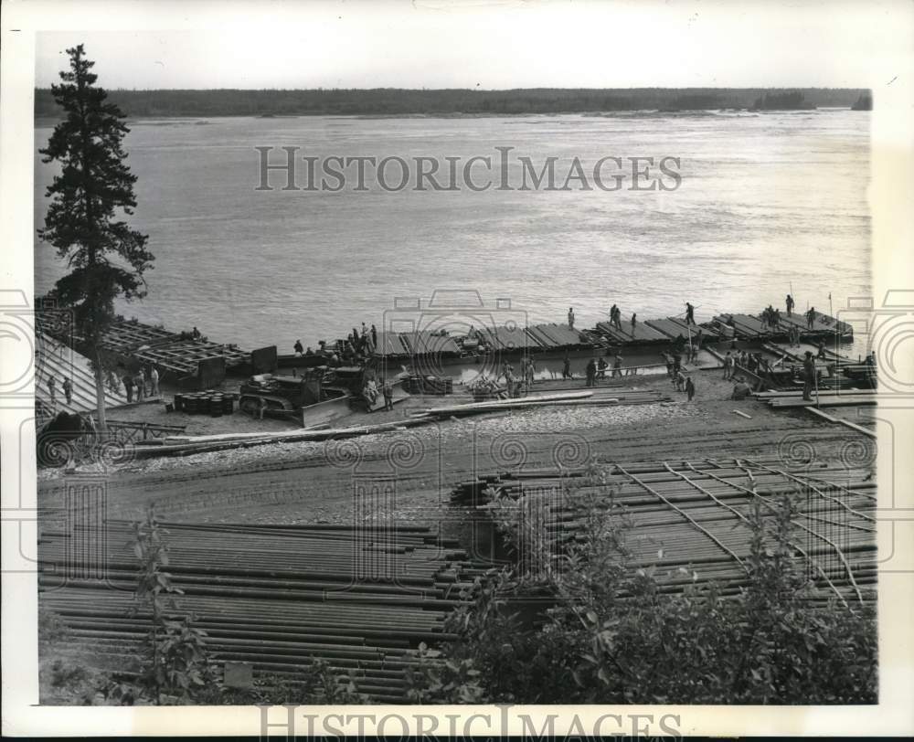 1943 Press Photo Men load oil pipes on barges at Slave River in Ft Smith, Canada - Historic Images