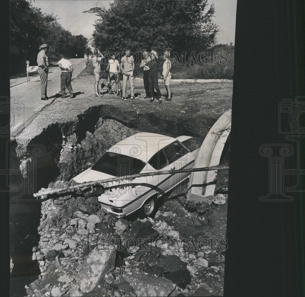 1968 Car in sink hole after rainstorm - Historic Images