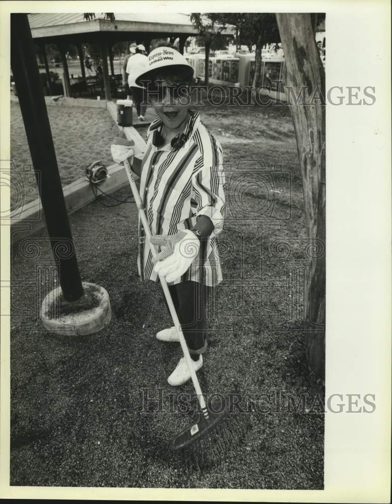 Press Photo Eli Dena raking leaves at playground, Texas - Historic Images