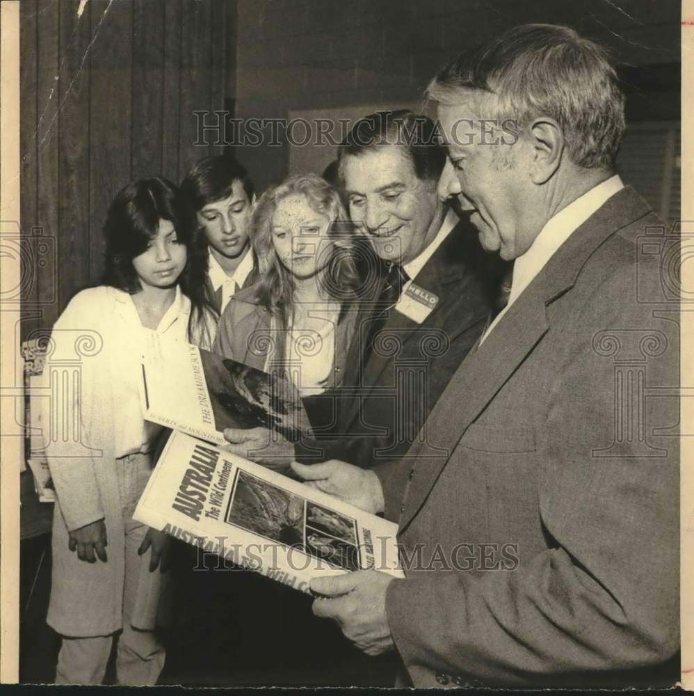 1981 Press Photo Frank Zingaro holds book on Australia, as others watch, Texas - Historic Images