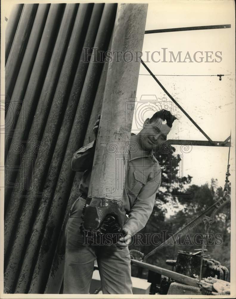 Worker putting a "Rock Bit" back into the hole at oil site-Historic Images