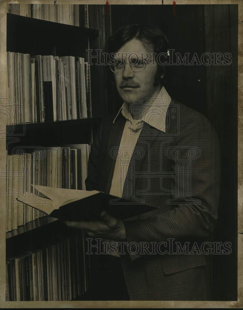 1975 Larry Hufford standing next to book case-Historic Images