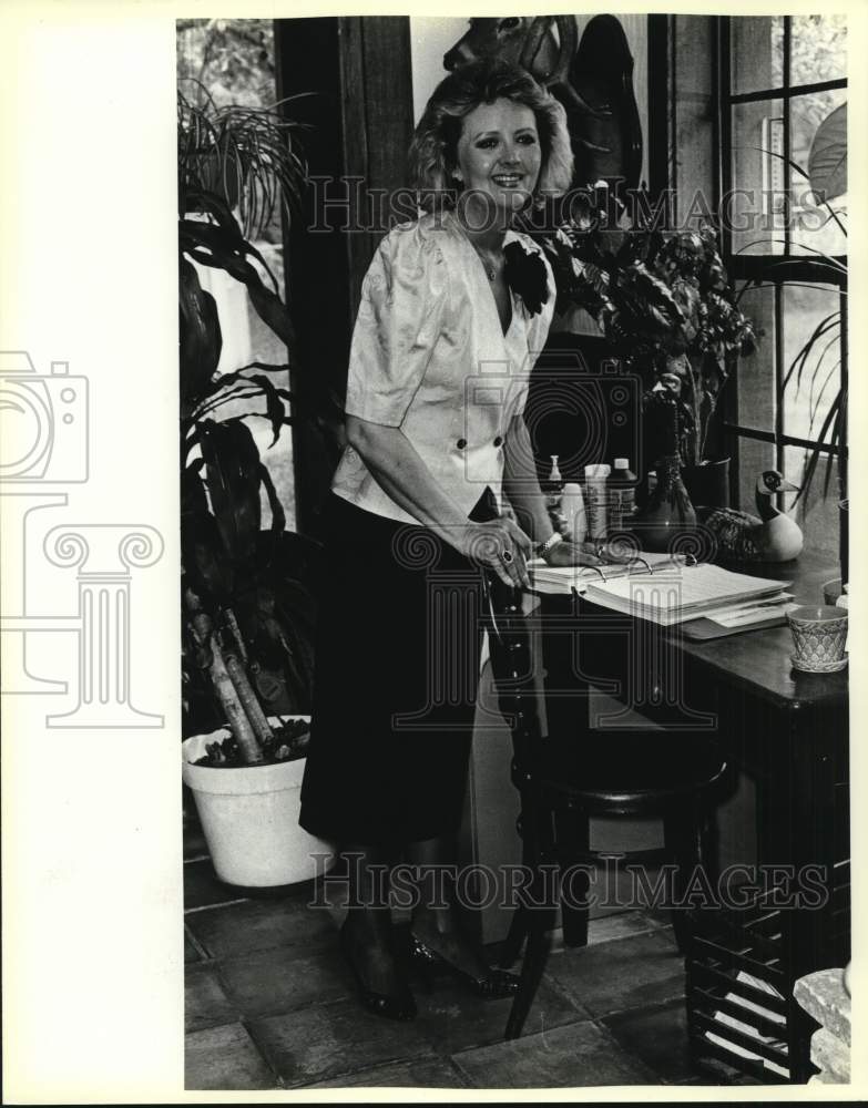 1986 Jane Hibler standing next to desk, Texas-Historic Images