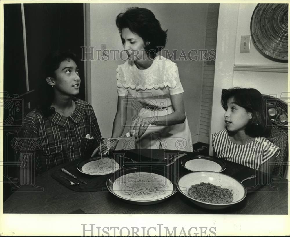 1985 Mary Alice Cisneros serving dinner to her daughters, Texas-Historic Images