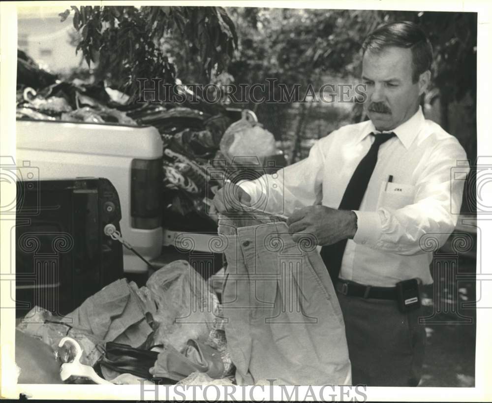 1988 Captain Jimmy Kopek looks over stolen clothes recovered Friday.-Historic Images