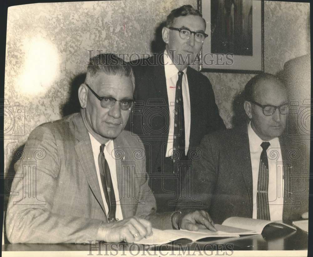 1960 W.H. McChesney looks through pamphlet with unidentified men.-Historic Images