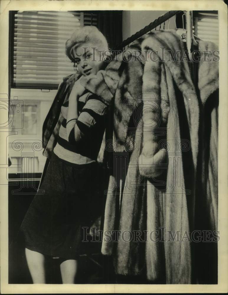 1961 Actress Abbe Lane models next to fur coats on hangers - Historic Images