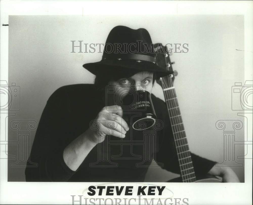 Press Photo Steve Key, Musician drinks from coffee cup with guitar - Historic Images