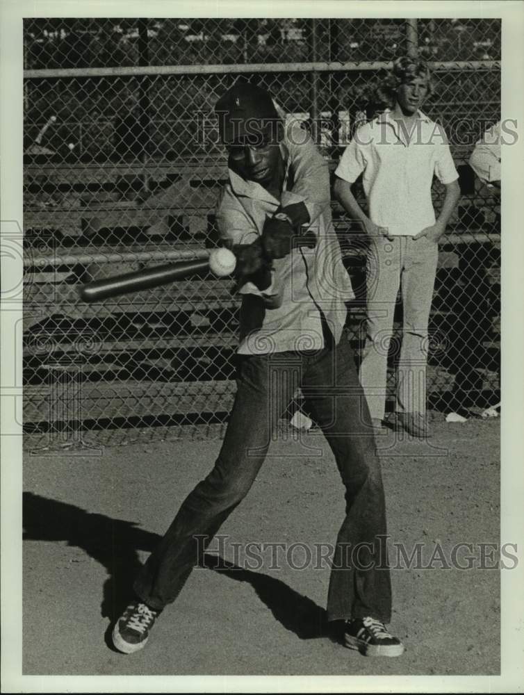 Press Photo A man hitting a baseball while people watch. - Historic Images