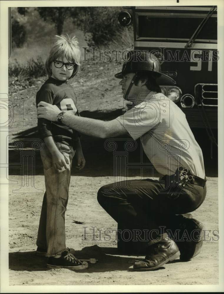 Actor portraying Firefighter with child in scene - Historic Images