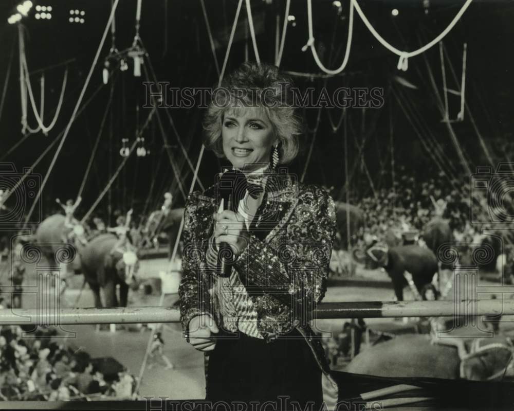 Press Photo Circus Performer Talks into Microphone as Elephants March in Ring - Historic Images