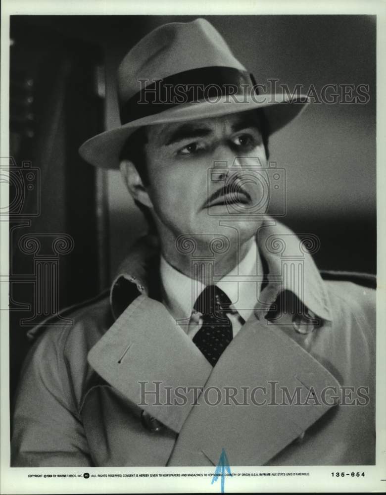 1984 Press Photo Actor Burt Reynolds in Trench Coat &amp; Hat in Warner Bros. Film - Historic Images