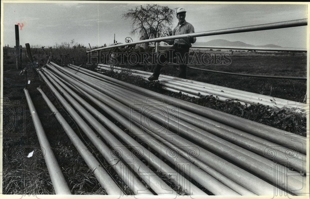 1987 Press Photo Dave Simonson stacks irrigation pipes on Hayden Lakes farm - Historic Images