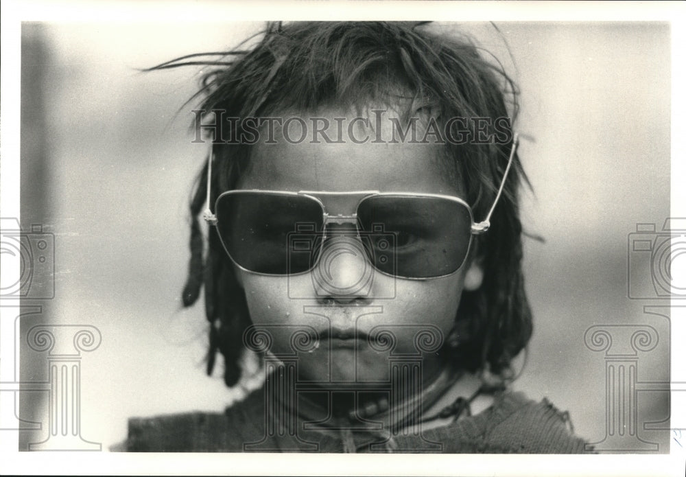 1987 Press Photo Tibetan girl wears her father's sunglasses at a Tibetan village - Historic Images