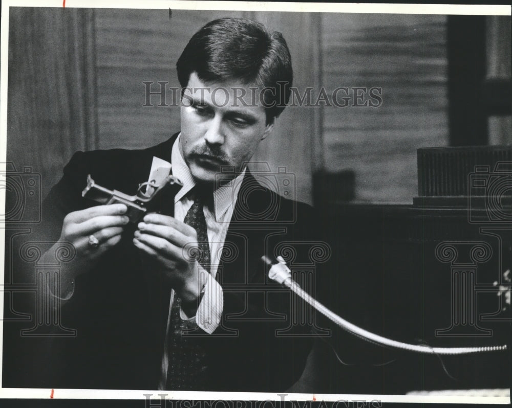1986 Jeff Burnside of KREM T-V holds a gun on witness stand-Historic Images