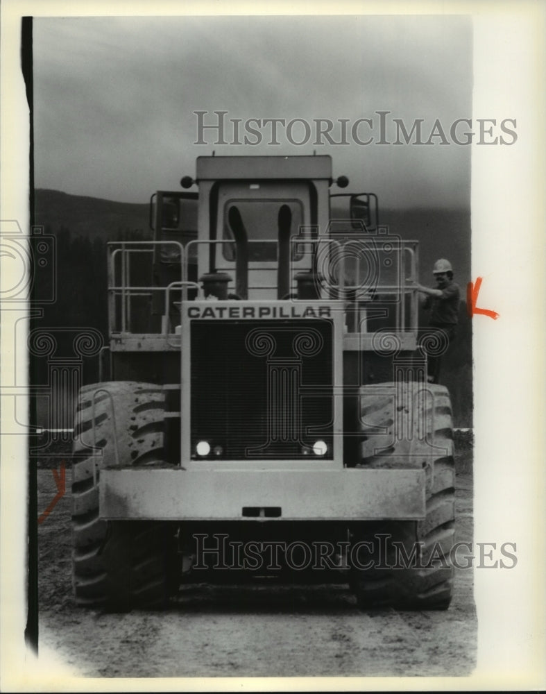 Press Photo Mt. Saint Helens, man standing on side of Caterpillar tractor - Historic Images