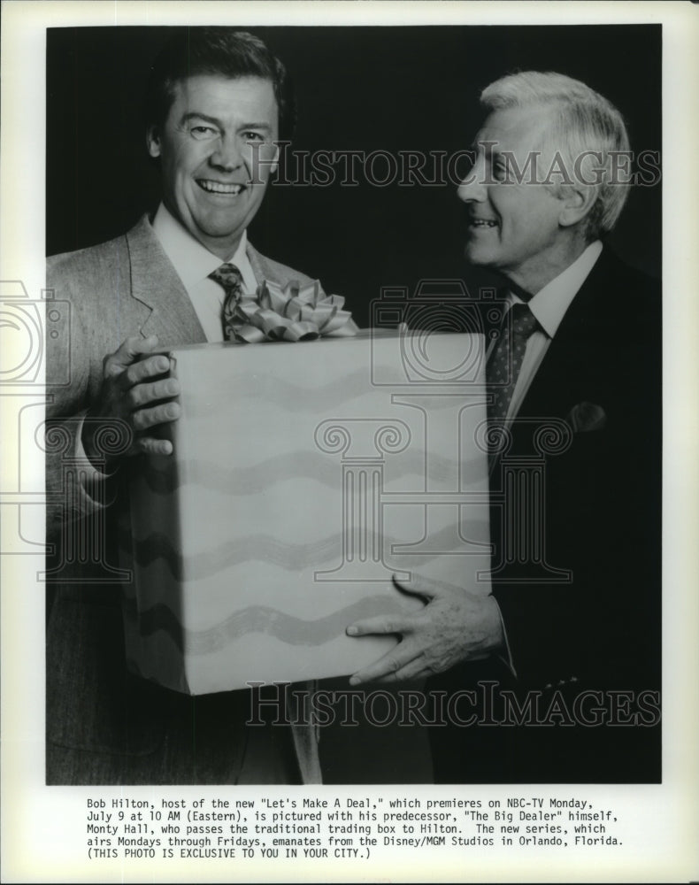 1990 Press Photo Monty Hall passes trading box to Bob Hilton "Let's Make A Deal" - Historic Images