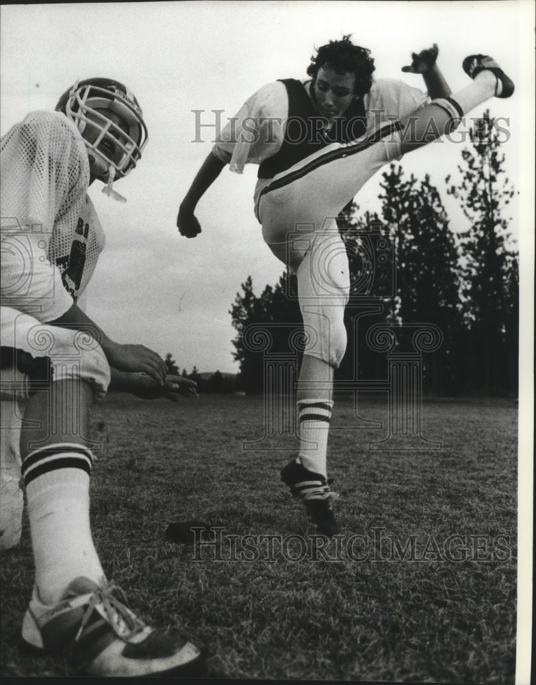 1983 Football player Darin Blakely kicks ball held by Jon Guthrie - Historic Images