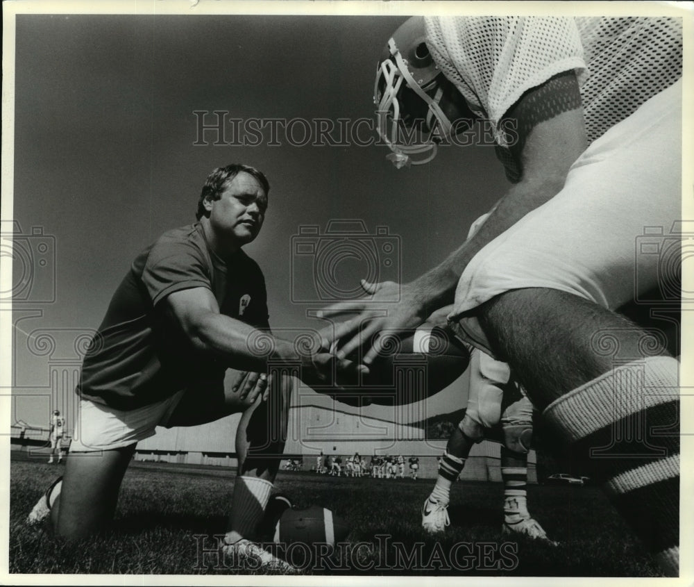 1987 Press Photo Larry Schwenke Hands the FootBall to a Player - sps13155 - Historic Images