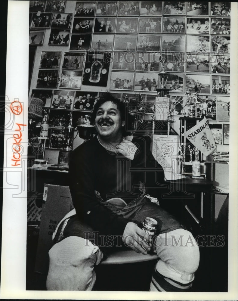 1985 Press Photo Hockey Player Gene Taylor Enjoys a Drink In Front of Photo Wall - Historic Images