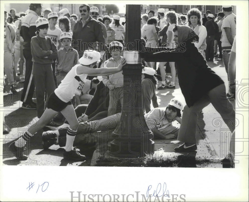 1985 Press Photo Bloomsday racers use a light pole to help them stretch - Historic Images