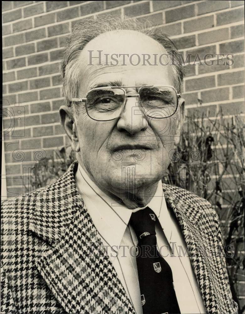 1976 Press Photo Mott A. Garlock posing next to brick wall - sra35114- Historic Images