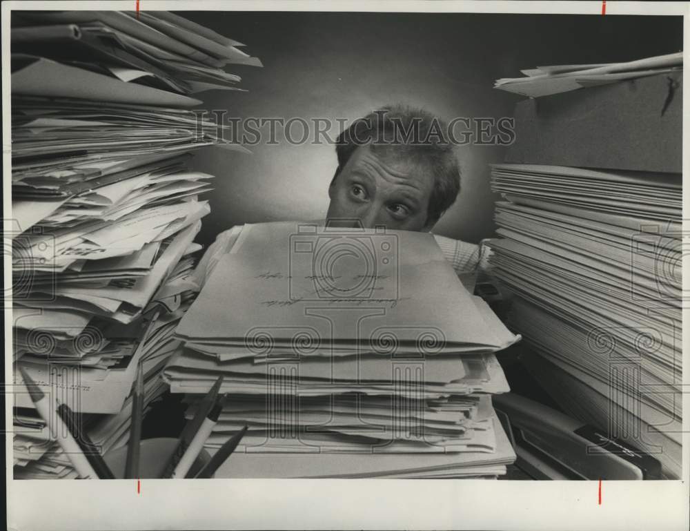 1987 Press Photo Man Looking from Behind Stacks of Paper in &quot;Form Phobia&quot; - Historic Images