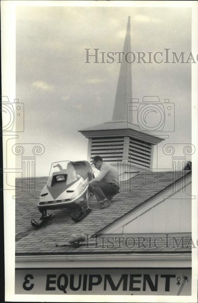 1985 Press Photo Auburn U-Haul Worker Ernie Leonard Straps Snowmobile to Roof - Historic Images