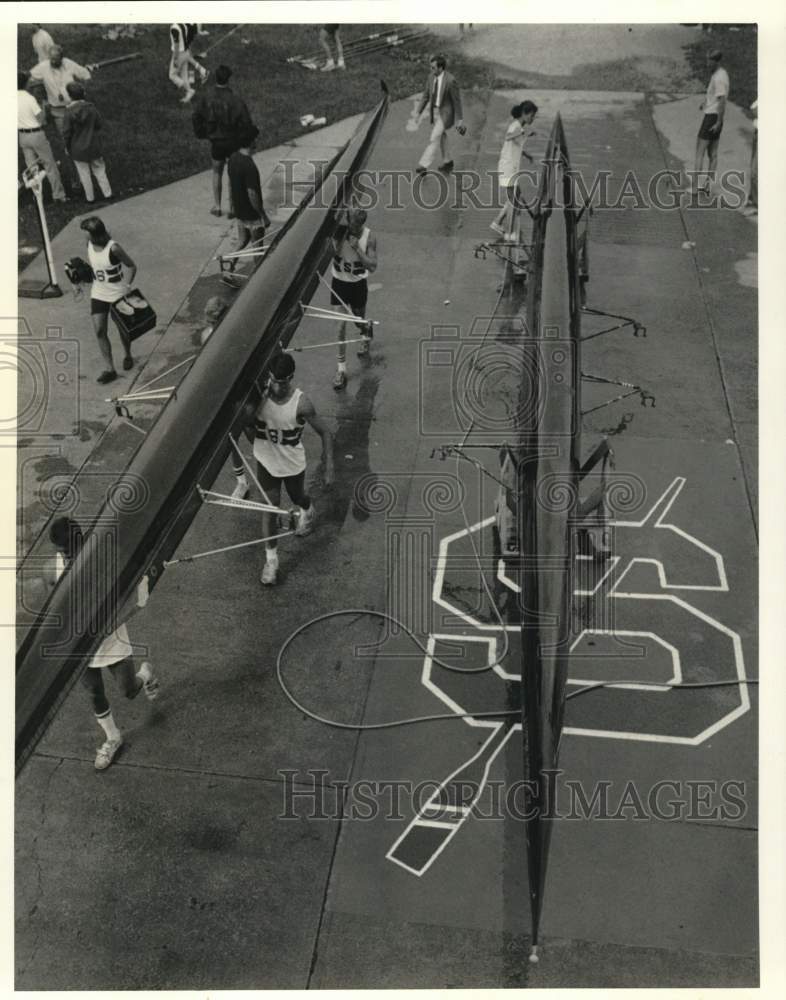 1986 Press Photo Crew Members Carry Boats at IRA Boat House - Historic Images