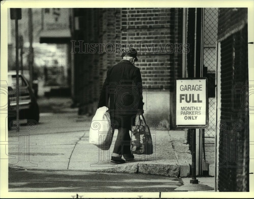 1989 Press Photo Homeless man carrying bags down Albany, New York sidewalk - Historic Images