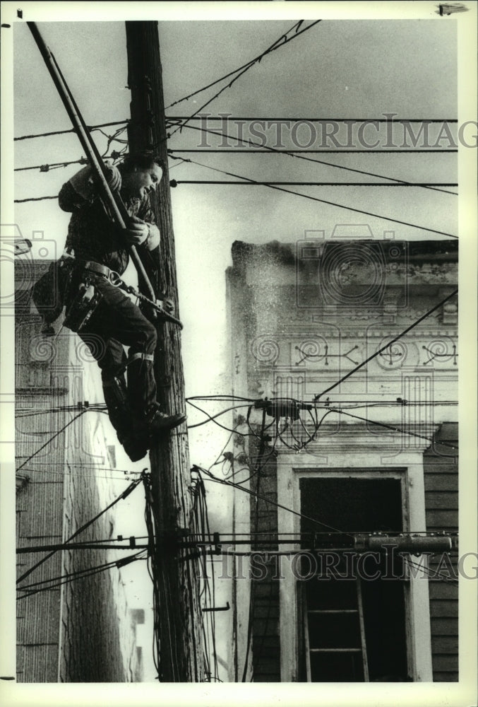 1989 Niagara-Mohawk lineman avoids spray from firehose in Albany, NY - Historic Images